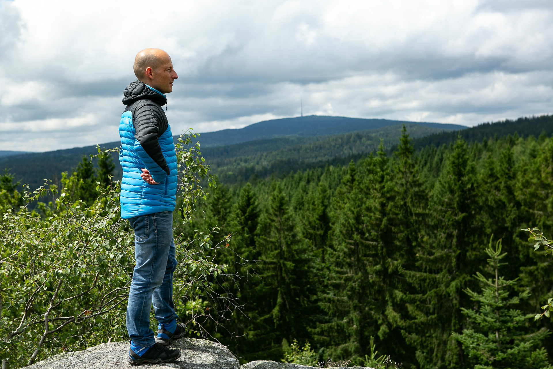 Thomas Postler steht auf einem Felsen mit Blick über eine bewaldete Landschaft